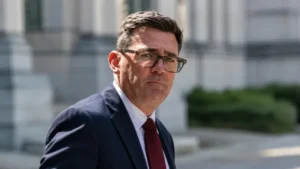 British politician wearing glasses and a suit outdoors in a professional setting