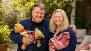 Adrian Higham net worth article image showing a smiling couple holding vintage teddy bears outdoors