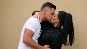 Couple embracing and kissing against a beige backgroun