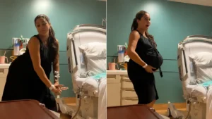 Pregnant woman standing beside a hospital bed in a teal room