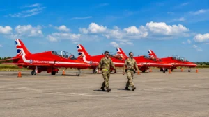Red Arrows aircraft lined up at an airfield with RAF personnel walking in front