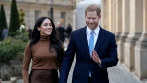 Smiling couple walking together outside a grand building, with the man in a navy suit giving a small wave